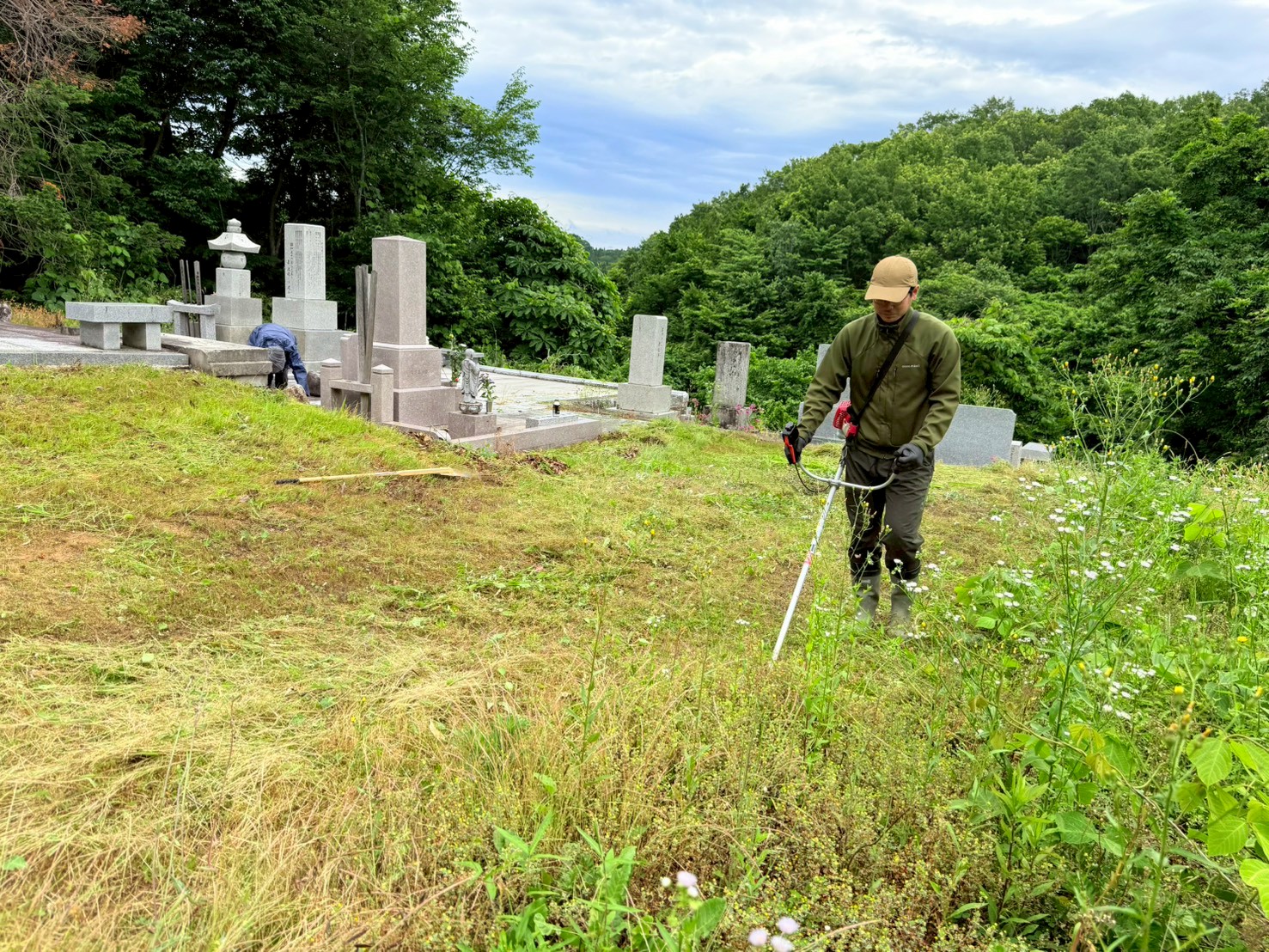 お墓の周りを刈払いする様子